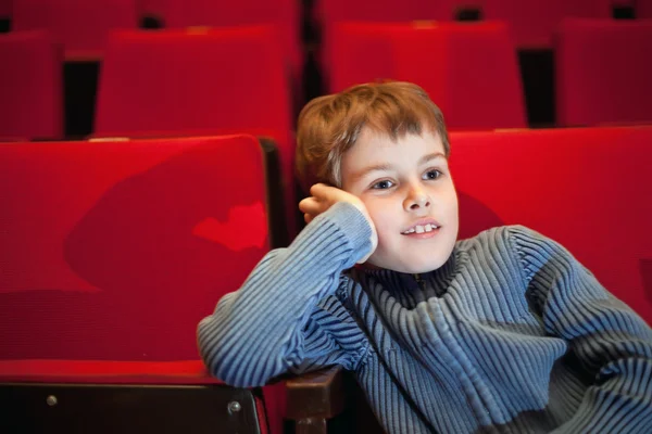 Boy sitting on armchairs at cinema, steadfastly looking — Stock Photo, Image