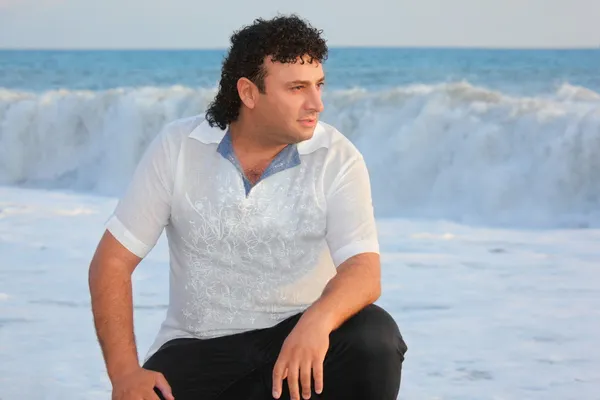 Один человек сидит у воды на берегу моря — стоковое фото