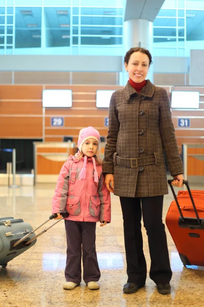 Młoda matka i dziewczynka z walizkami stojący w porcie lotniczym — Zdjęcie stockowe