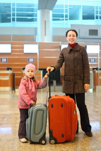 Junge Mutter und kleines Mädchen mit Koffern stehen am Flughafen — Stockfoto