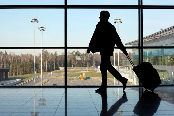Silhouette eines Mannes mit Gepäck, der in der Nähe eines Flugzeugfensters geht — Stockfoto