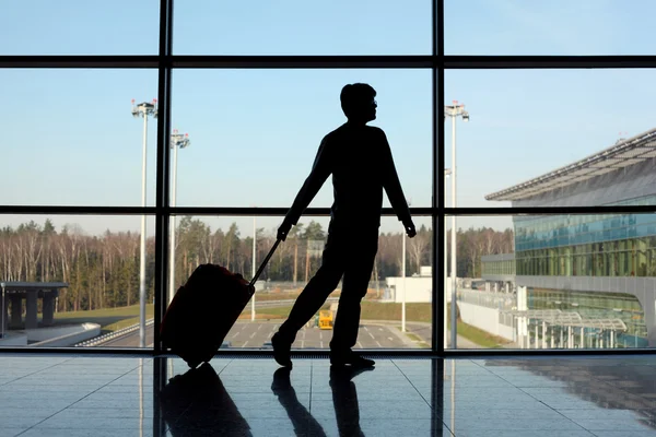 Silhouette of man with luggage walking right near window in airp — Stock Photo, Image