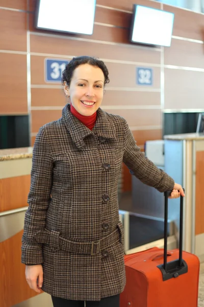 Jeune femme attrayante avec valise rouge debout à l'aéroport — Photo