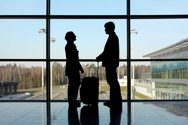 Silhouet van man en meisje met bagage staan in de buurt van venster in — Stockfoto