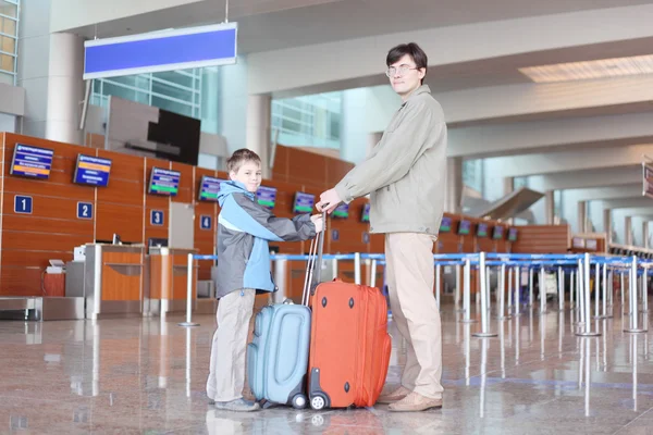 Pai e filho com mala vermelha em pé no lado do corredor do aeroporto — Fotografia de Stock