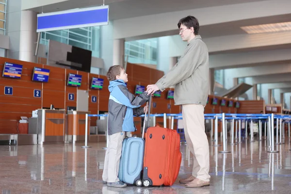 Padre e hijo con maletas de pie en la sala del aeropuerto vista lateral —  Fotos de Stock