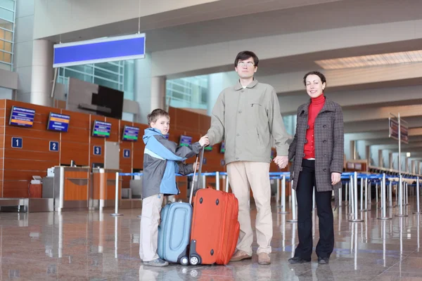 Семья с мальчиком, стоящим в зале аэропорта с чемоданами полного тела — стоковое фото