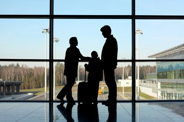 Silhouette of family with luggage standing near window in airpor — Stock Photo, Image