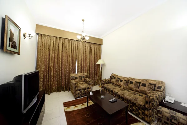 Гостиная с коричневым диваном, креслами и закрытой телевизионной шторкой — стоковое фото