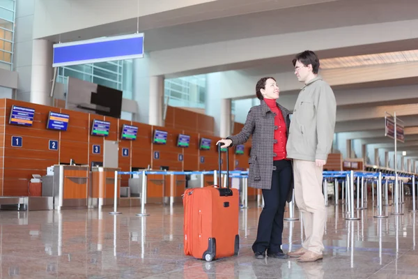 Mannen och flickan med röd resväska står i flygplatsen hall — Stockfoto