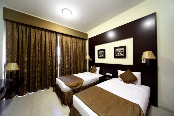Slaapkamer met witte muren, gesloten bruine gordijn en twee bedden gen — Stockfoto