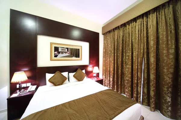 Schlafzimmer mit weißen Wänden, geschlossenem braunen Vorhang und großem Doppelbett — Stockfoto