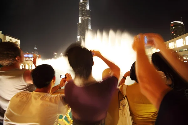 Tourists in Dubai recording video and taking photos at night abs — Stock Photo, Image