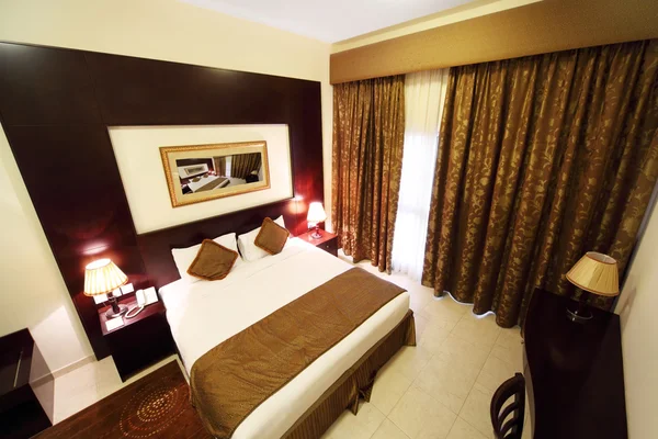 Dormitorio con paredes blancas, cortina marrón y gran vista a la cama doble — Foto de Stock