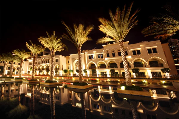 Noche Dubai street con palmeras y piscina, Emiratos Árabes Unidos — Foto de Stock