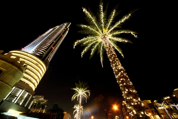 Noche Dubai palmeras con lámparas de decoración y rascacielos, United Arab E — Foto de Stock