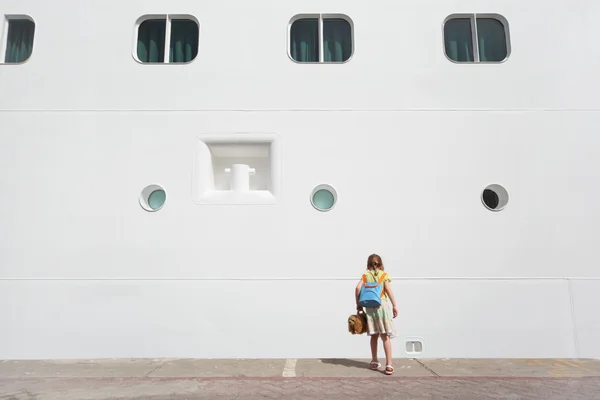 Little girl looking down near large white passenger liner at do — Stock Photo, Image
