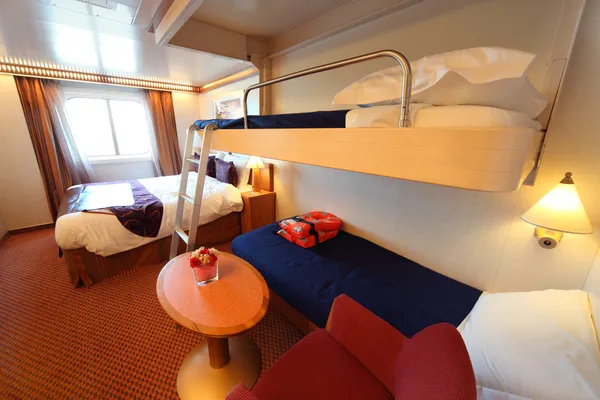 Каюта корабля с окном, большой двуспальной кроватью и двумя детскими кроватями. — стоковое фото
