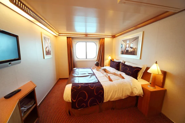 Mały chłopiec znajduje się na duże podwójne łóżko w sumie Widok ogólny kabiny statku — Zdjęcie stockowe