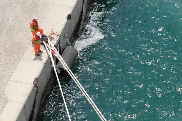 Due lavoratori in uniforme ormeggiano una nave a vista di giorno estiva dall'alto — Foto Stock