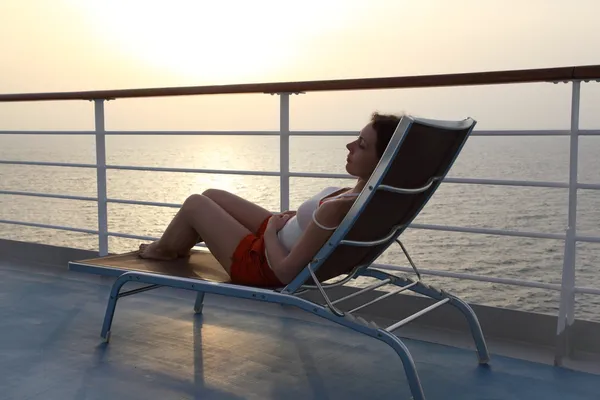 Девушка, сидящая на пляжном стуле на палубе корабля вид сбоку всего тела — стоковое фото