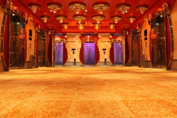 Moderno salão de luxo com teto vermelho brilhante e elevadores vista frontal — Fotografia de Stock