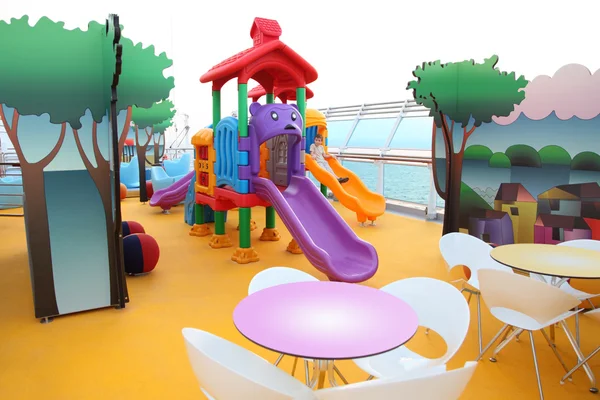 Pequeno menino desliza no parque infantil colorido brilhante em cru — Fotografia de Stock