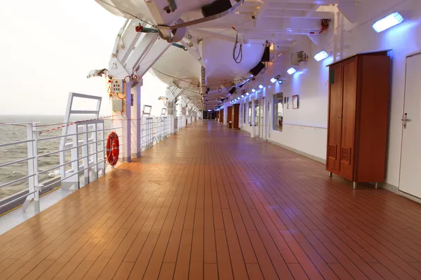 Kreuzfahrtschiff-Deck mit braunem Holzboden und eingeschalteten Lampen an — Stockfoto