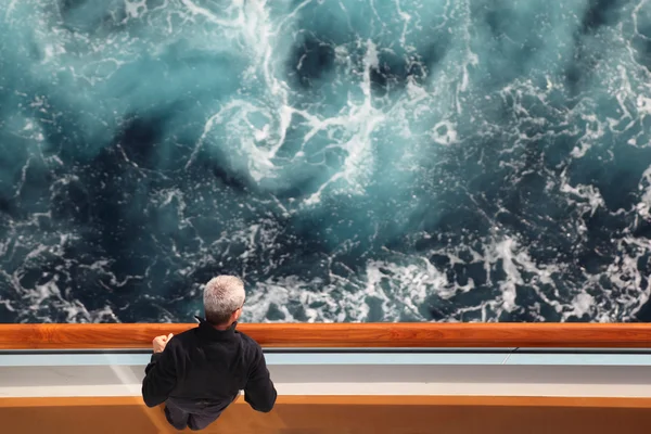 Hombre de pie en la cubierta del crucero y mirando a la vista lateral de un —  Fotos de Stock