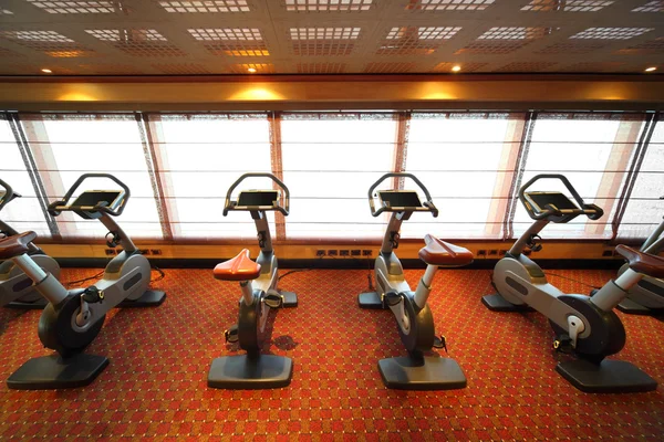 Büyük spor salonunda egzersiz Bisiklet penceresinde yakınındaki cruise gemisi — Stok fotoğraf