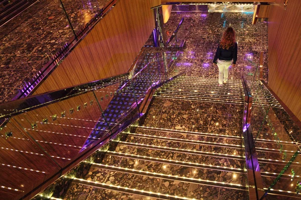 Девушка спускается по ступеням большой яркой лестницы со множеством декоров — стоковое фото