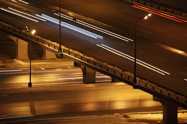 Cidade noturna com ponte e iluminação colunas de tráfego rodoviário com tr — Fotografia de Stock