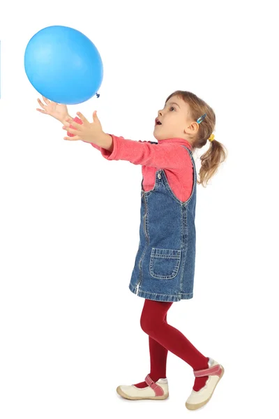 Little girl in jeans dress playing with blue balloon side view i — Stock Photo, Image
