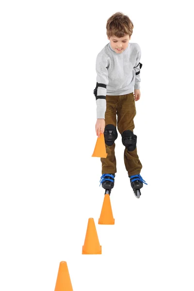 Kleiner Junge mit Kegel in der Hand beim Inlineskaten in der Nähe orangefarbener Kegel — Stockfoto