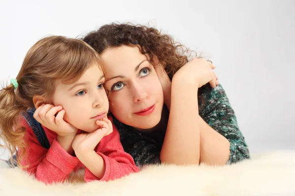 Little girl and her mother lies on white fell, hands on chin,loo — Stock Photo, Image