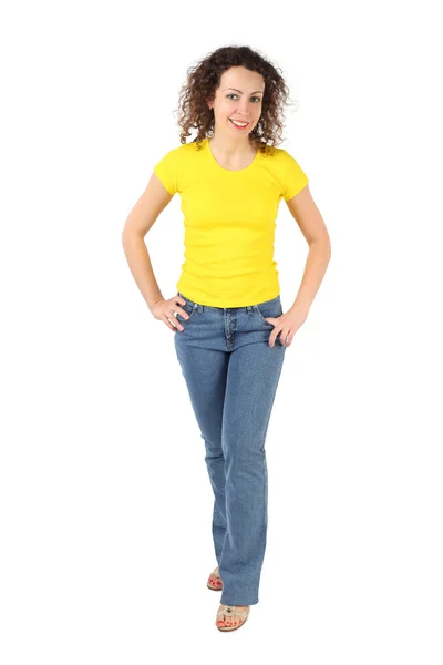 Молодая привлекательная женщина в желтой рубашке и джинсах стоя, руки — стоковое фото