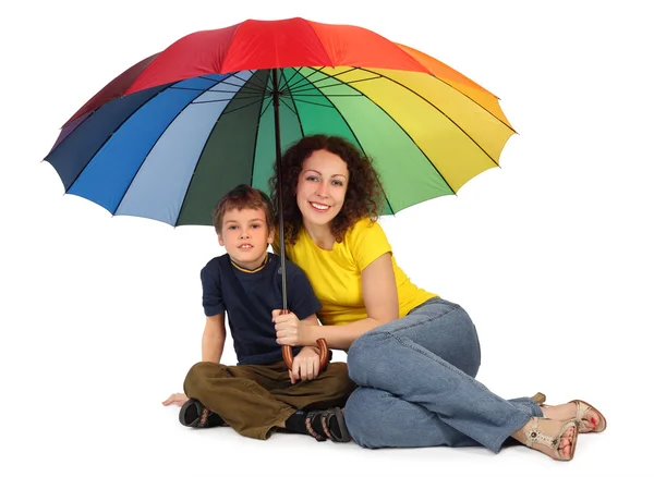 Мать и сын с большим разноцветным зонтиком сидит изолированы о — стоковое фото