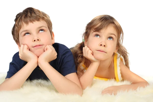 Little boy and girl lying on white fell, chin on hands, looking — Stock Photo, Image