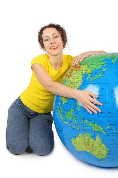 Piękna młoda kobieta siedzi w pobliżu duży nadmuchiwany Globus i uśmiechając się — Zdjęcie stockowe