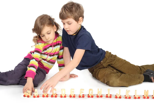 小男孩和女孩玩坐在地板上的木铁路 — 图库照片