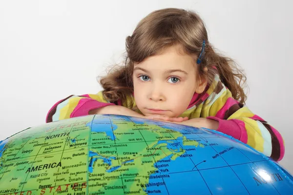 Petite fille se trouve sur grand globe gonflable, menton sur les mains, regardant — Photo