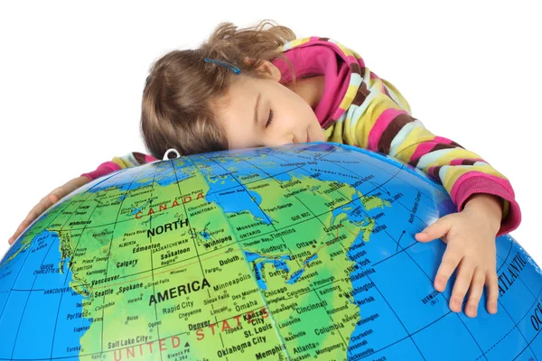 Маленькая девочка лежит на большом надувном глобусе и обнимает его, глаза — стоковое фото