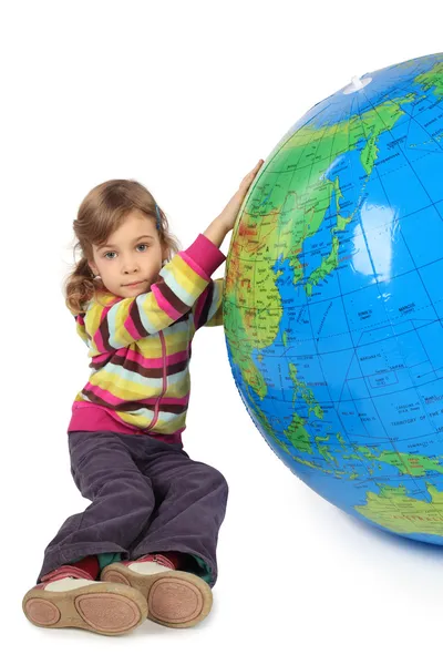Dziewczynka siedzi w pobliżu duży nadmuchiwany Globus i trzymając go, lo — Zdjęcie stockowe
