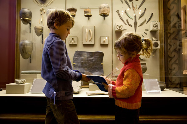 Мальчик и девочка на экскурсии в историческом музее рядом с выставкой
