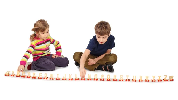 小男孩和女孩玩坐在地板上的木铁路 — 图库照片