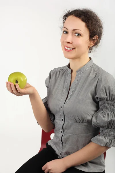 Fiatal vonzó nő tartja az alma az egyik kezében, nézi — Stock Fotó