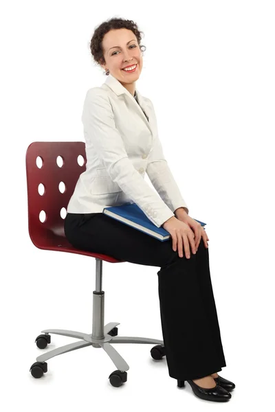 Junge attraktive Frau im Businesskleid sitzt auf Stuhl und hockt — Stockfoto