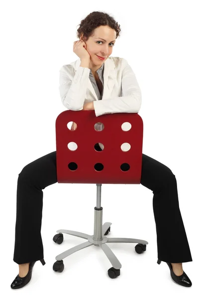 Jonge aantrekkelijke vrouw in zakelijke jurk zittend op rode stoel is — Stockfoto