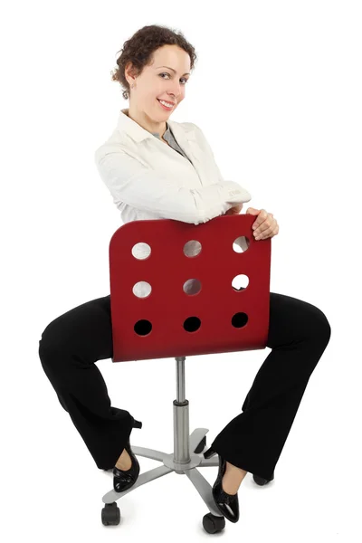 Junge Schönheit im Businesskleid sitzt auf einem roten Sessel und — Stockfoto