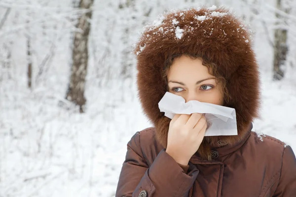 Młoda kobieta z szalik dmuchanie nosa w drewnie w zimie — Zdjęcie stockowe